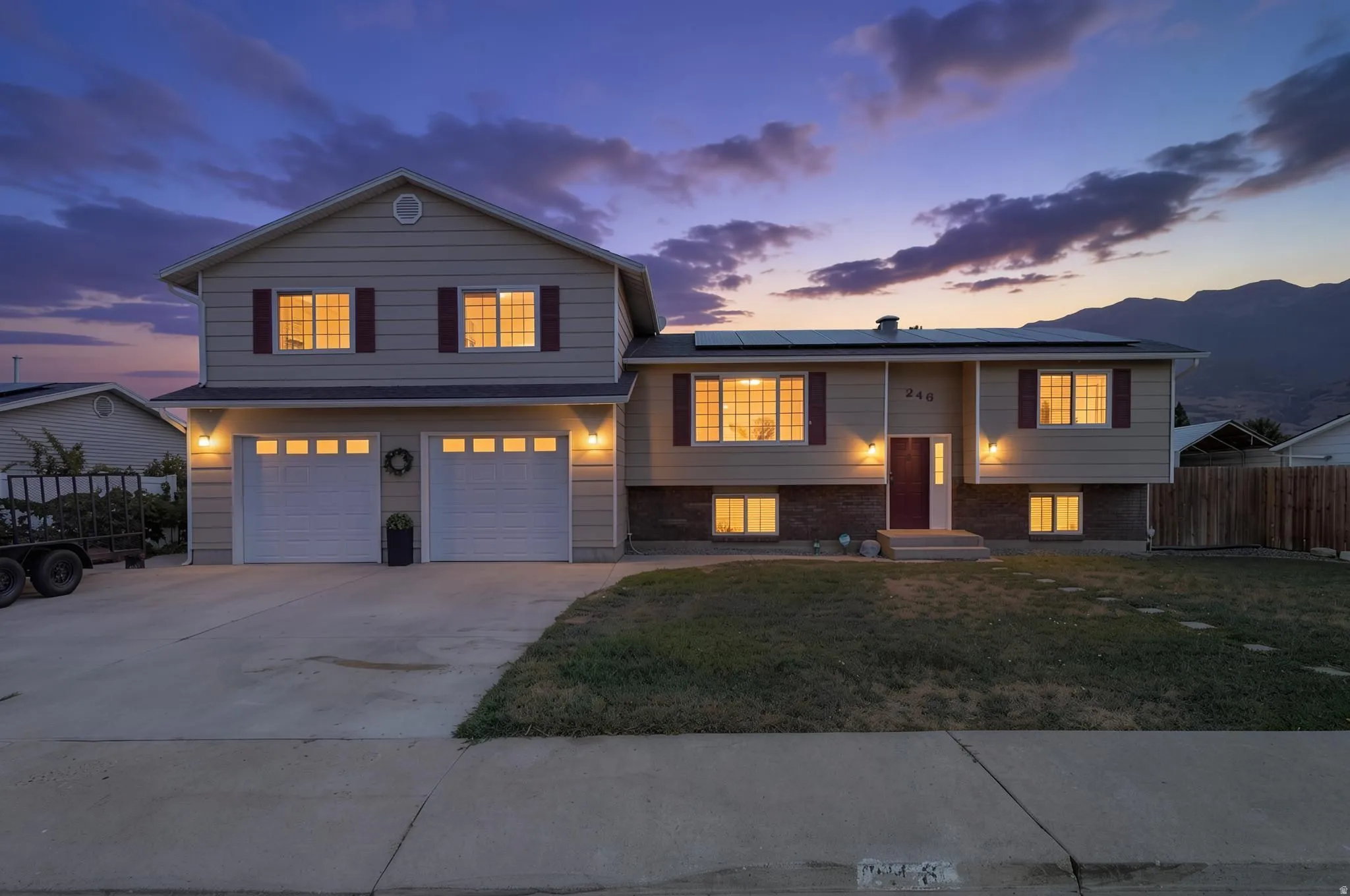 Two-story residence featuring a two-car garage, front yard with stepping stones, and a fenced side yard