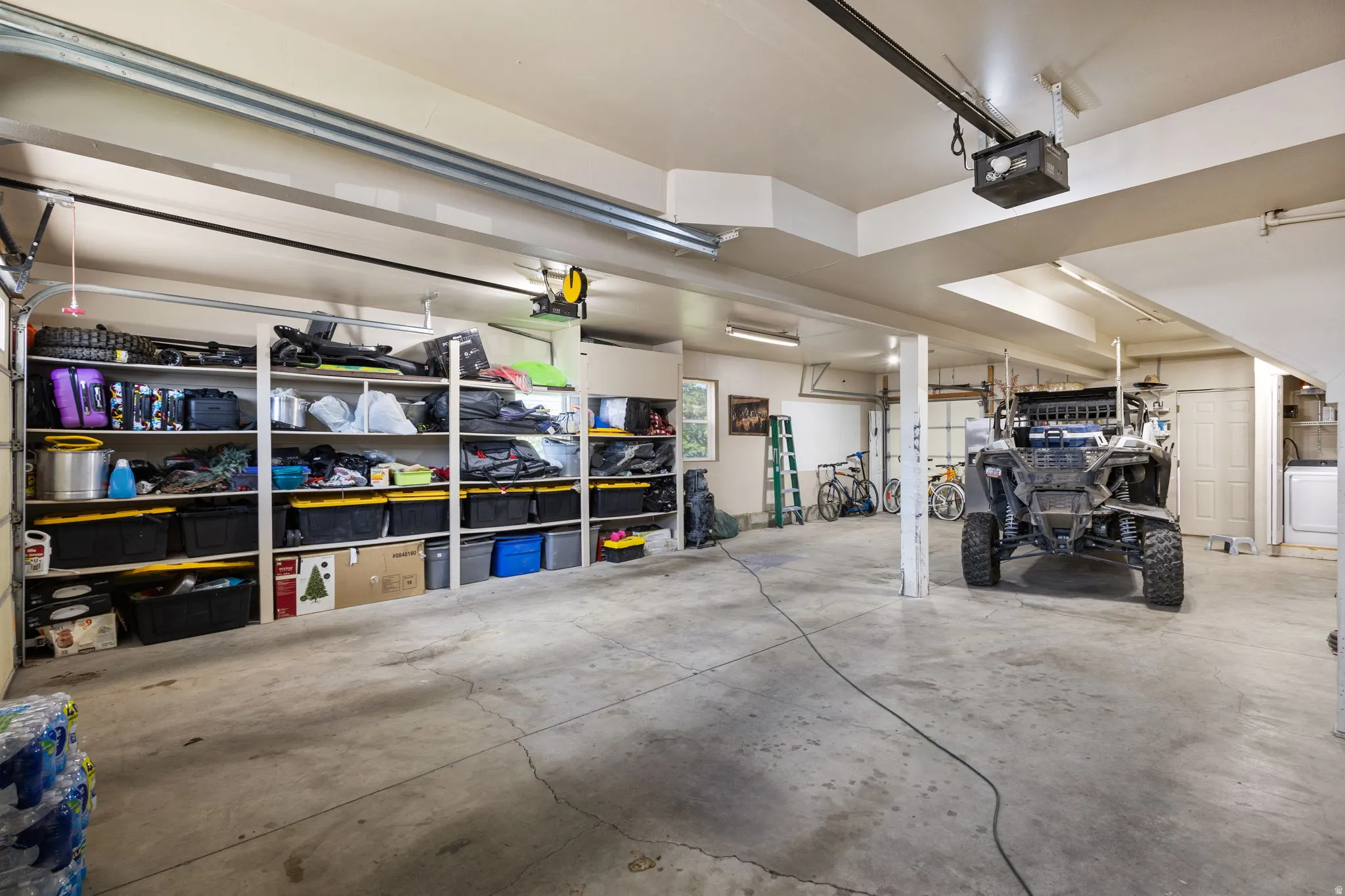 Spacious garage featuring concrete flooring and extensive built-in shelving