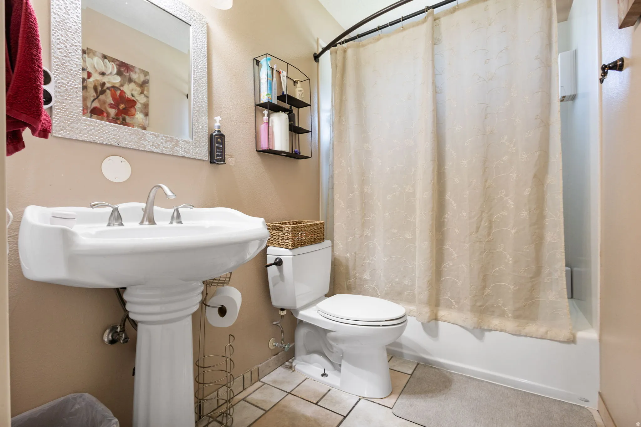 Pedestal sink with a brushed nickel faucet, framed mirror, and a full bathtub with a shower curtain
