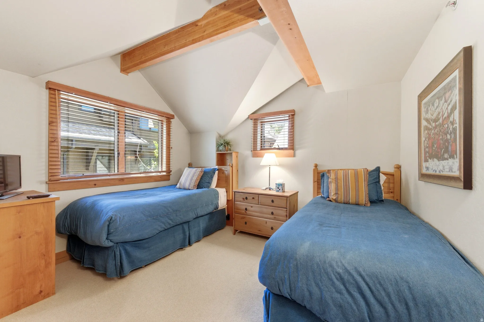 Bright, vaulted bedroom with exposed wood beam ceiling and multiple windows flooding the space with natural light