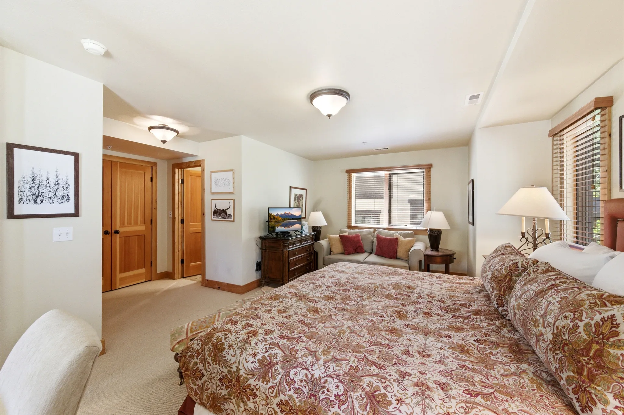 Spacious bedroom featuring dual bed frames, wood-finish flooring, and abundant natural light from multiple windows