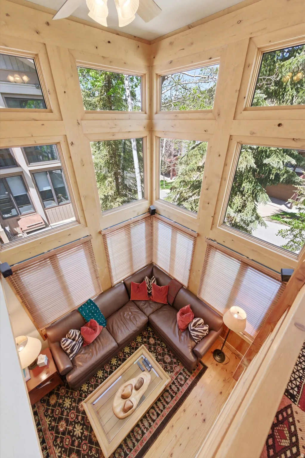 Wood-paneled walls and ceiling, multi-pane windows, wood-finish flooring, and a ceiling fan