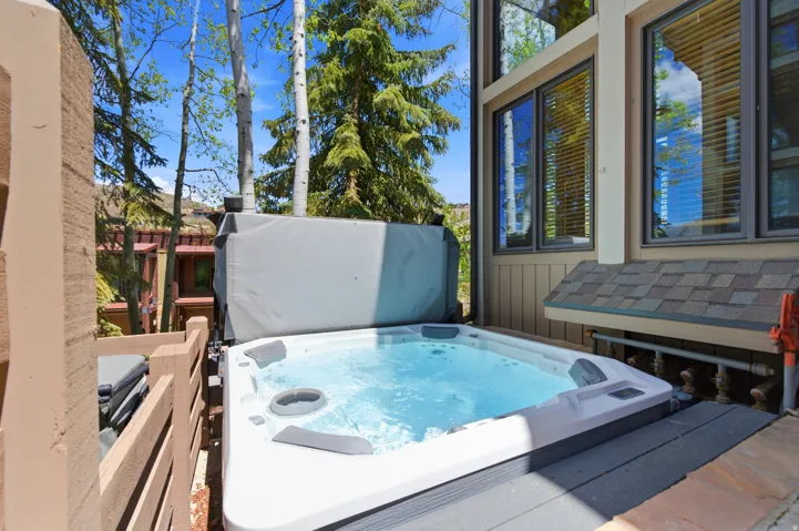 Luxurious spa-style hot tub with integrated seating jets and cover positioned on a composite deck