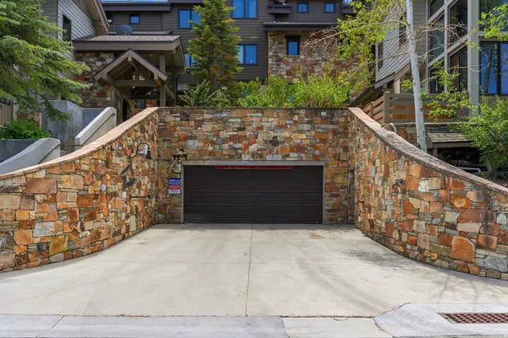 Stone veneer retaining wall with a paved driveway and built-in garage