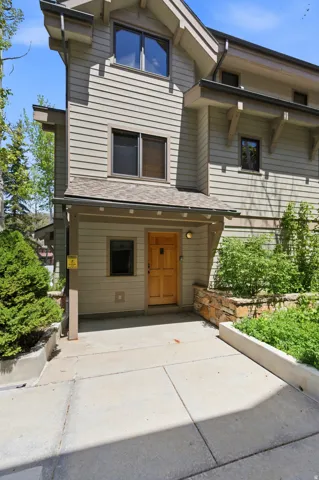 Modern multi-level residence featuring clean horizontal siding, a welcoming wood-finish entry door with sidelights, and a covered front entry
