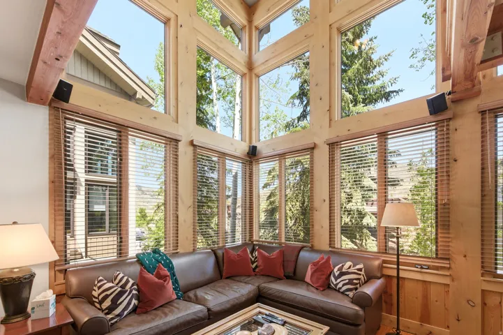 Two-story window wall featuring wood-framed windows, exposed timber beams, and wood paneling