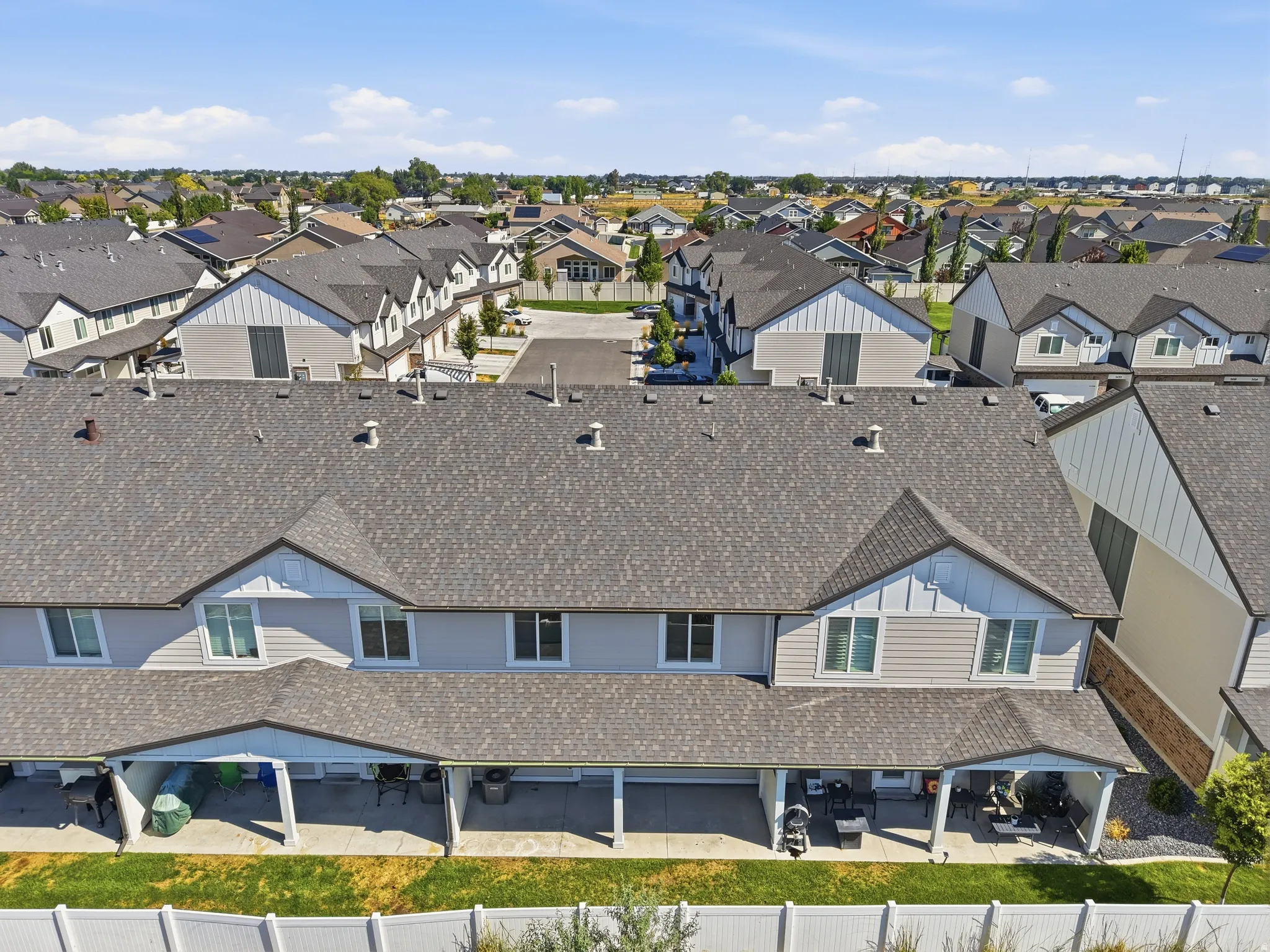 Townhome exterior featuring multiple covered patios, a fenced yard, and a shingle roof