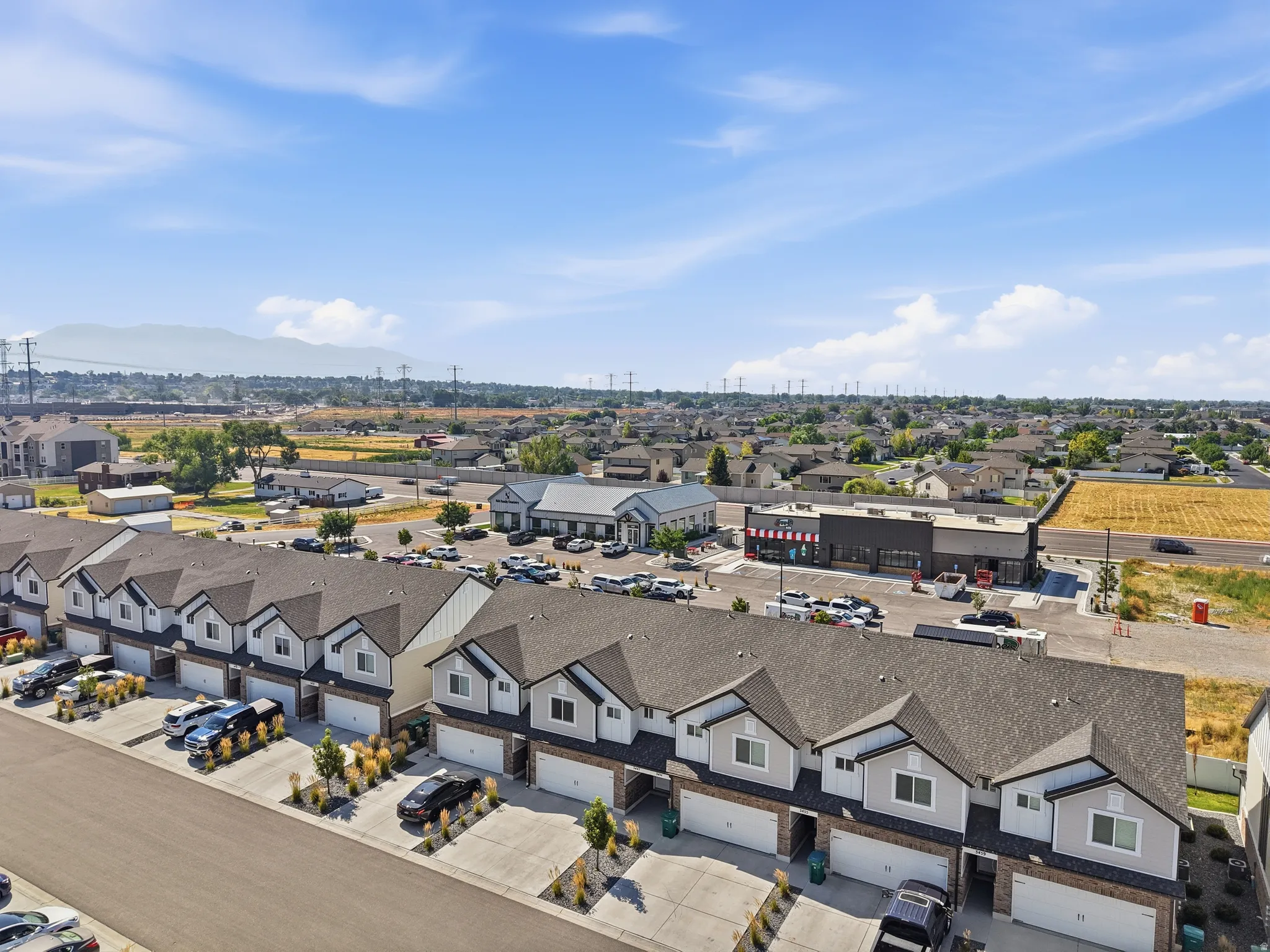 Townhome community featuring individual attached garages, defined front landscaping, and proximity to commercial establishments