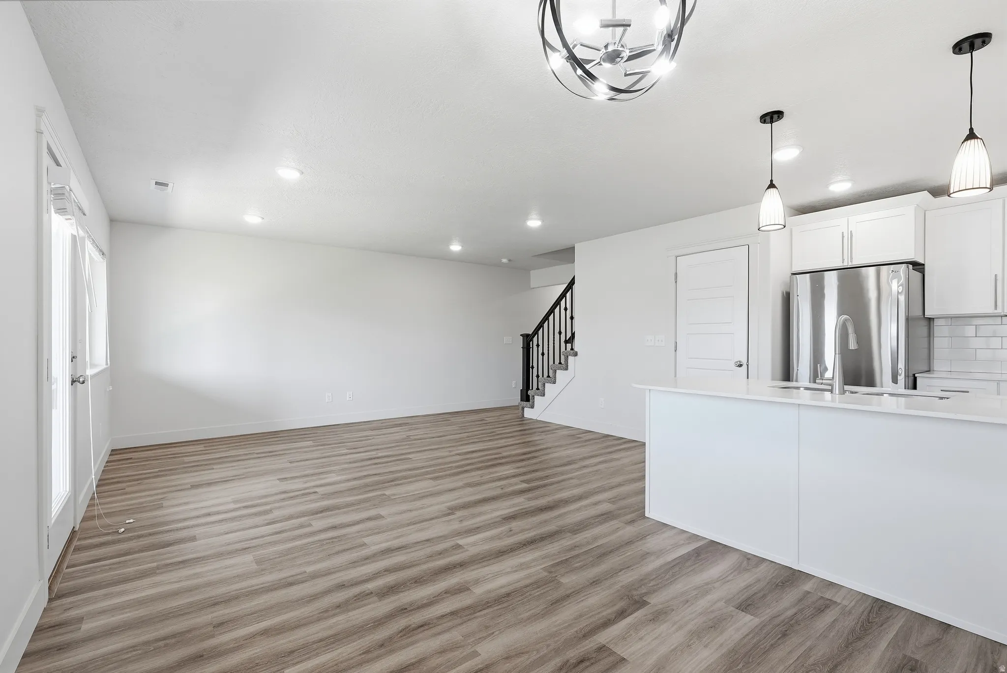 Open-concept living area featuring wood-finish flooring, recessed lighting, and a modern kitchen island
