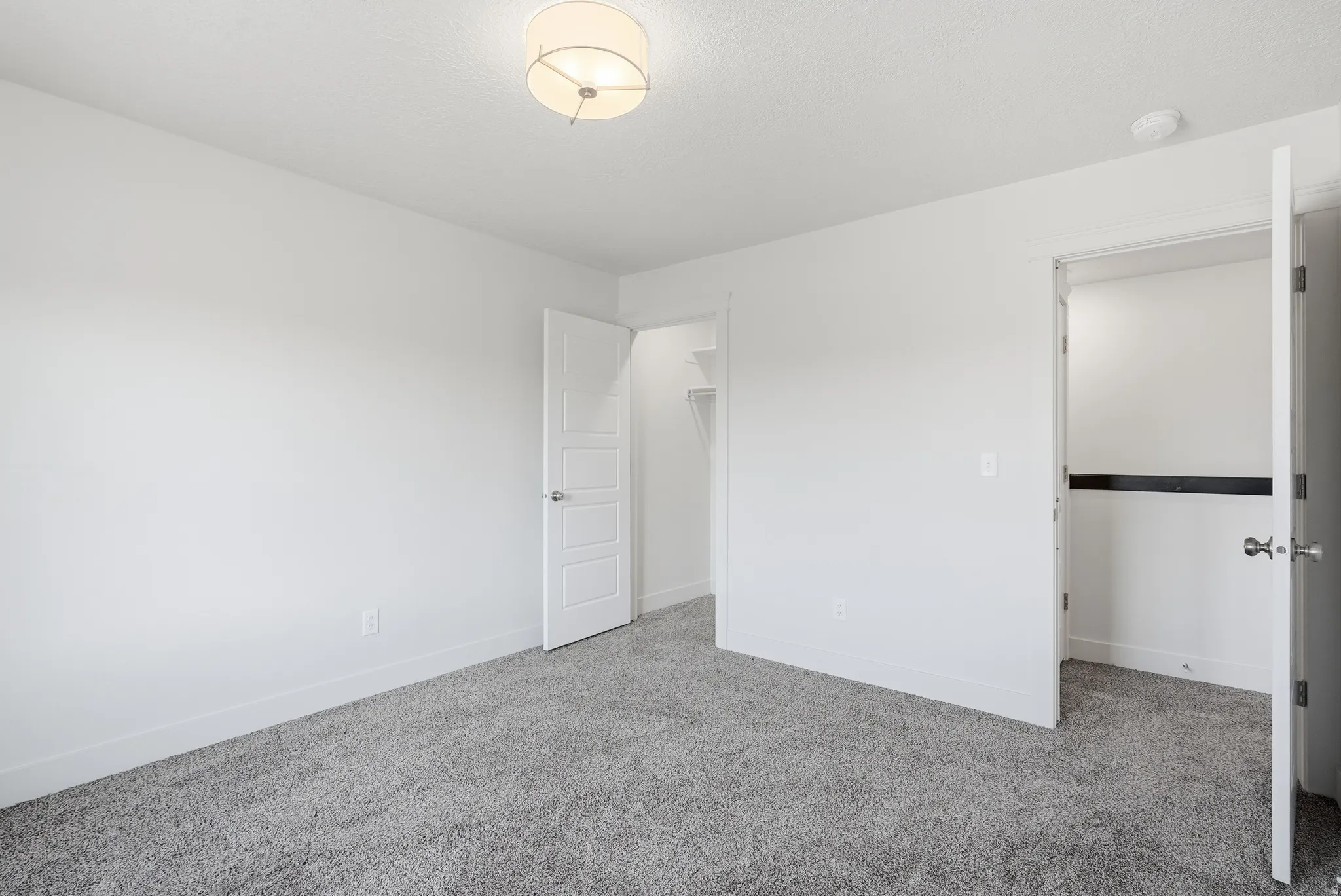 Gray textured carpeting, white walls, and a contemporary ceiling light fixture