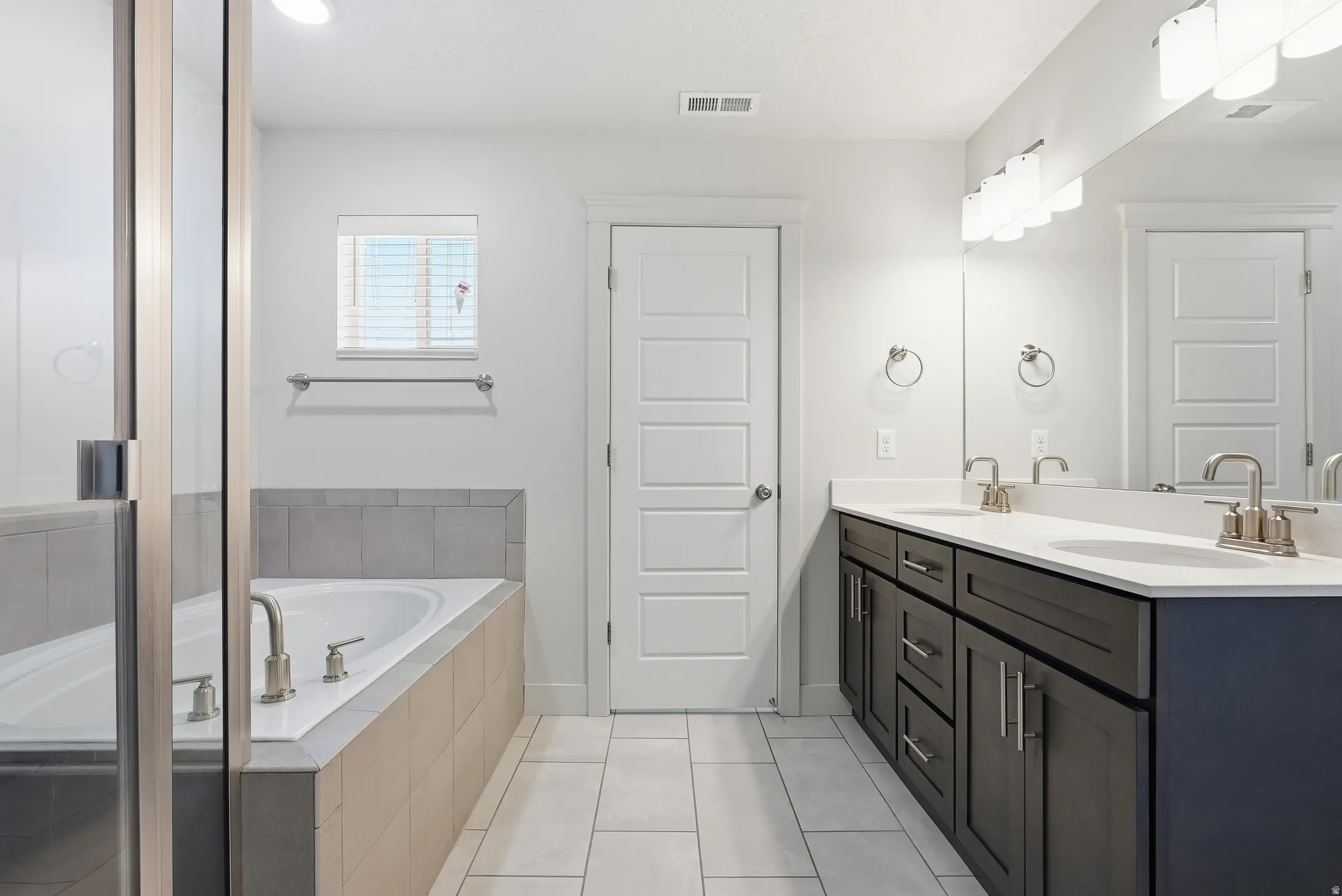 Dual vanity with dark wood-finish cabinetry, white countertops, and chrome fixtures