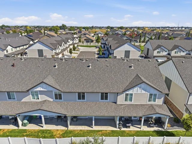 Townhome exterior featuring multiple covered patios, a fenced yard, and a shingle roof