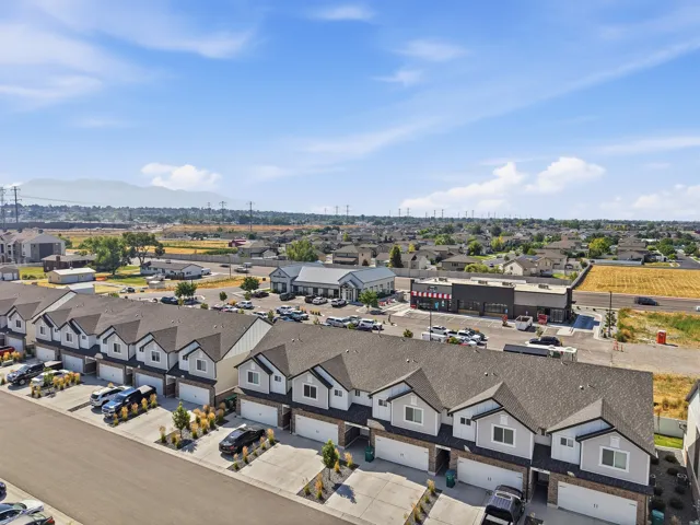 Townhome community featuring individual attached garages, defined front landscaping, and proximity to commercial establishments
