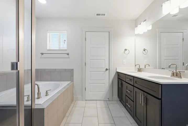 Dual vanity with dark wood-finish cabinetry, white countertops, and chrome fixtures