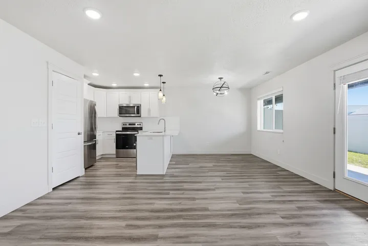 Modern kitchen featuring white cabinetry, stainless steel appliances, and an island with a sink