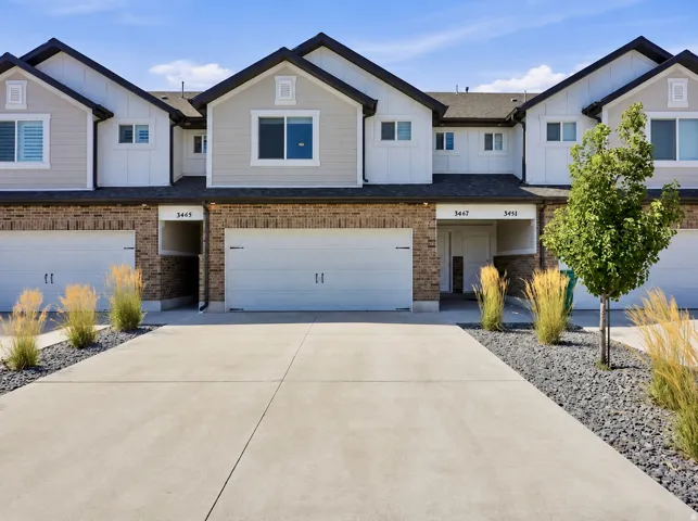 Modern townhome exterior featuring brick and siding facade, private garage, and concrete driveway