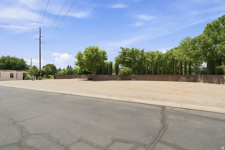 Expansive lot featuring a compacted gravel surface and a brick retaining wall