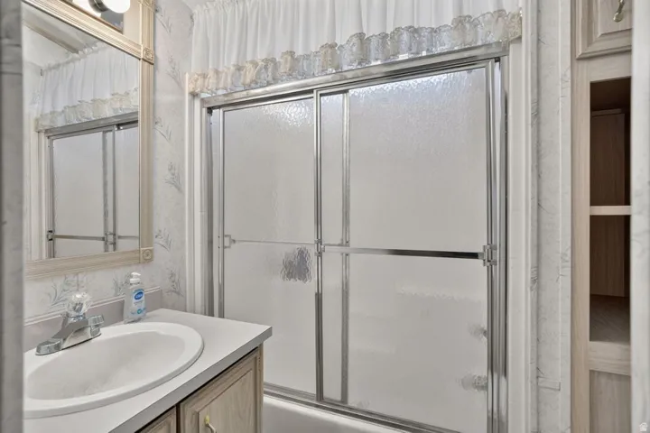 Frosted glass shower enclosure with chrome hardware, white vanity with an integrated sink, polished chrome faucet, and a framed vanity mirror