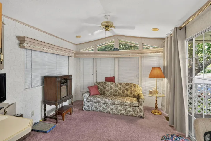 Sliding glass door, multiple transom windows, ceiling fan, recessed lighting, and wall-to-wall carpeting