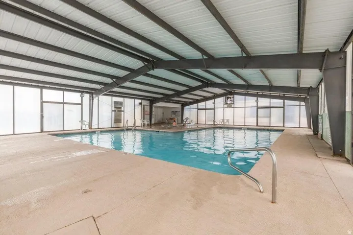 Enclosed swimming pool with a metal frame structure, translucent wall panels, and a concrete deck