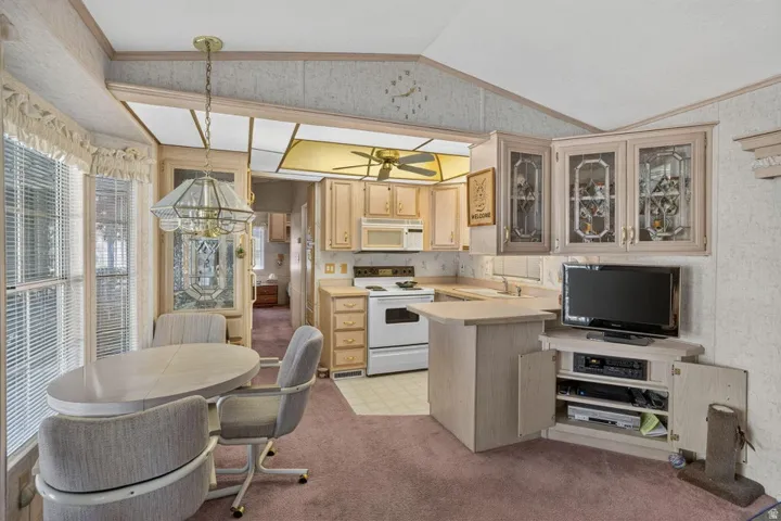 Kitchen with wood-finish cabinetry, white appliances, and a ceiling fan