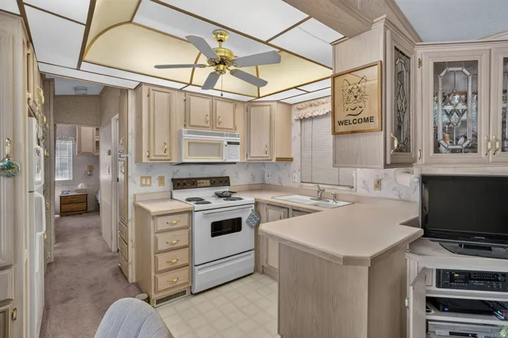 Kitchen featuring light wood-finish cabinetry, a ceiling fan, and laminate countertops