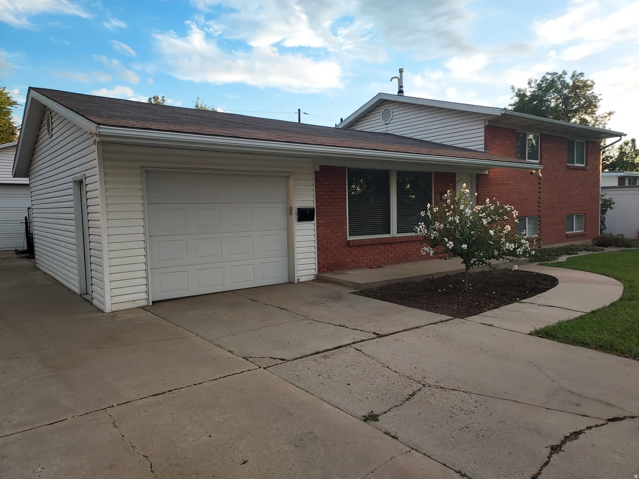 Brick Colonial home with attached garage featuring white overhead doors and concrete driveway