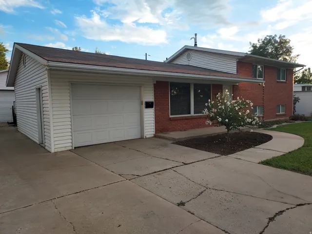 Brick Colonial home with attached garage featuring white overhead doors and concrete driveway