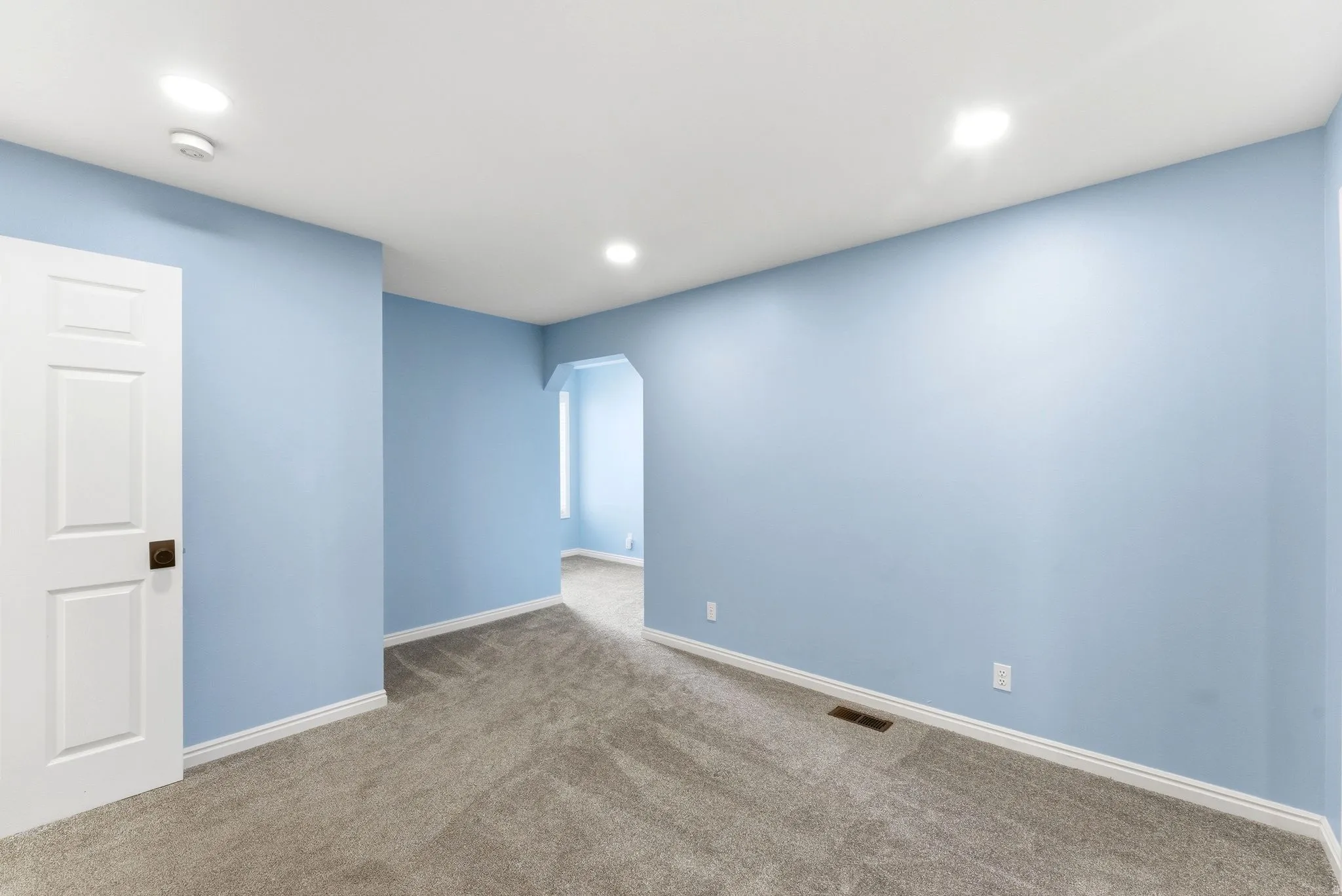Room featuring light blue walls, white trim, and gray carpeting
