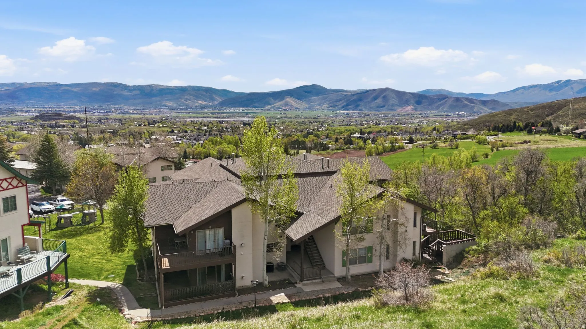 Contemporary multi-level residence featuring a pitched shingle roof, integrated balconies, and exterior stairs