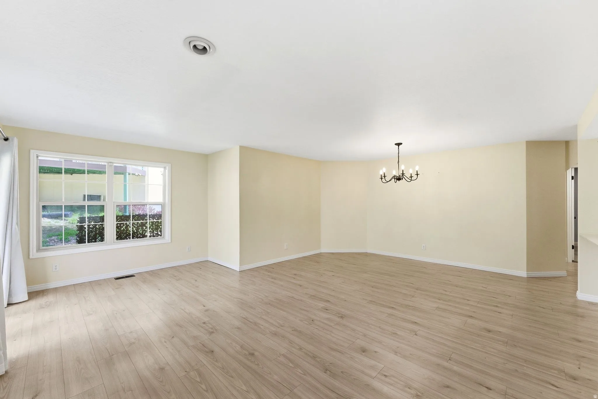 Spacious interior with wood-finish flooring, light-toned walls, and a large multi-pane window