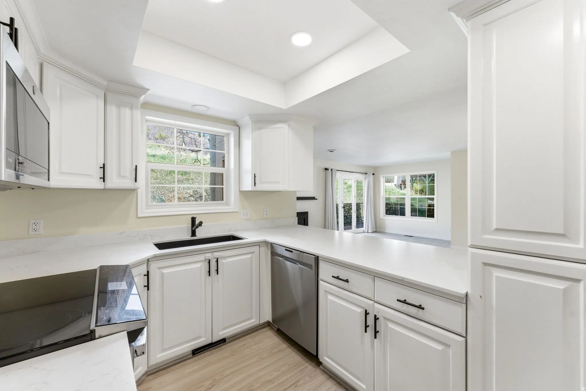 Kitchen featuring white cabinetry, light-toned countertops, stainless steel appliances, and wood-finish flooring
