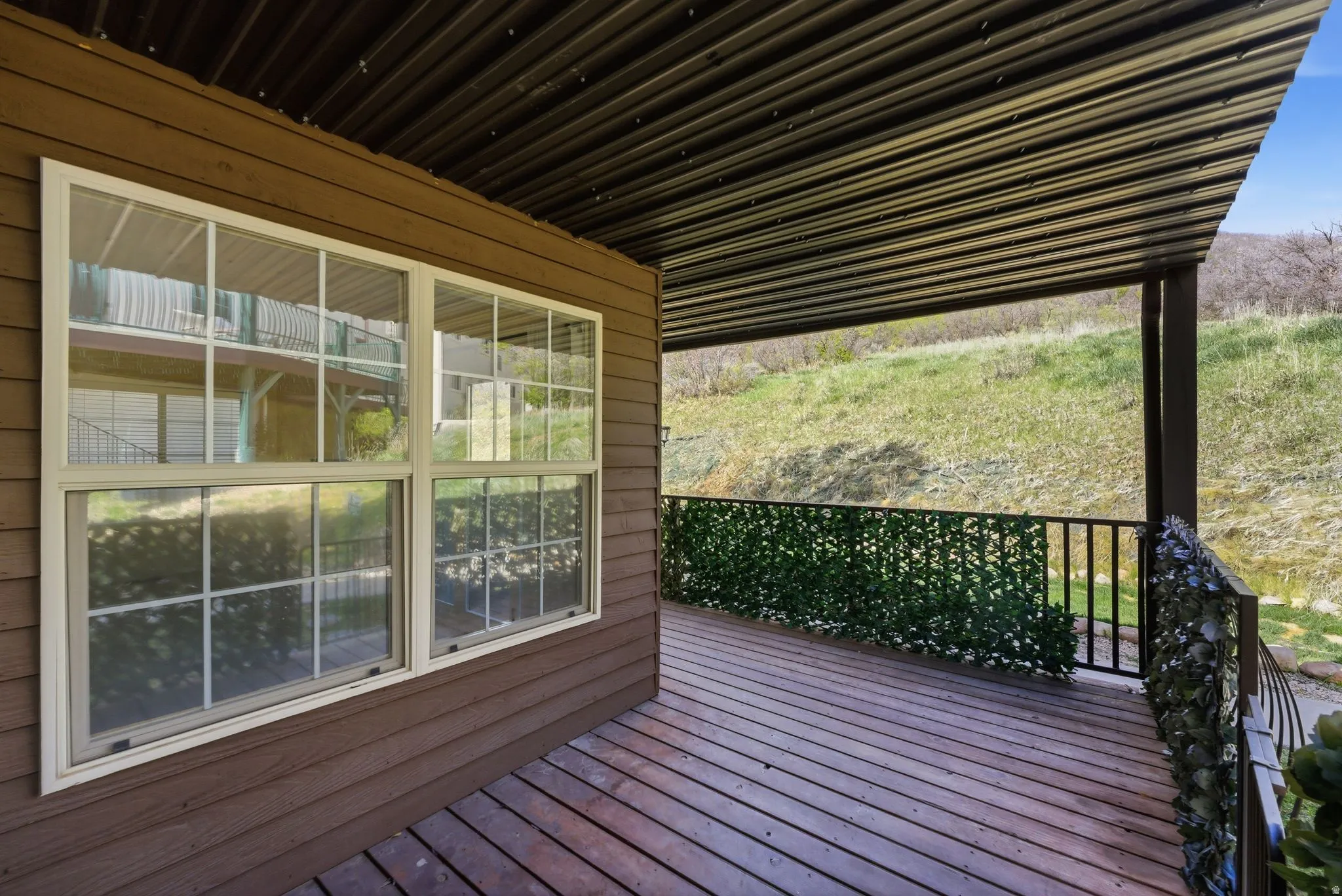 Spacious outdoor deck featuring wood-finish flooring and a slatted metal ceiling