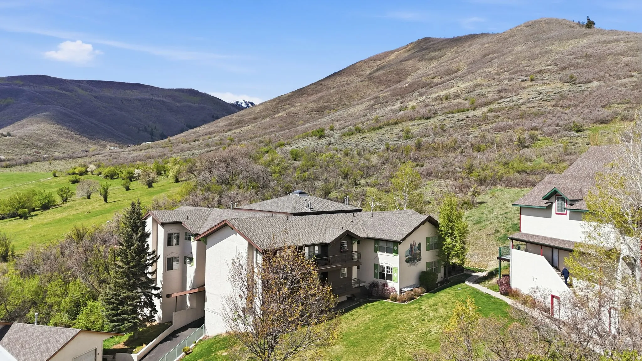 Multi-level property featuring a hillside setting with mature trees and landscaping