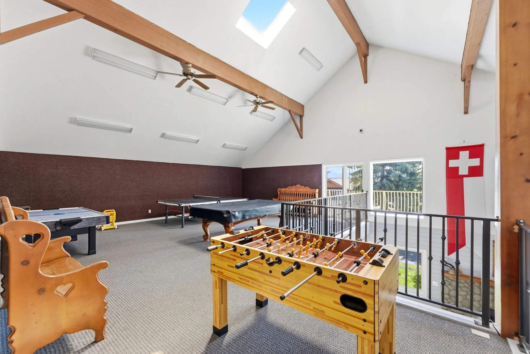Spacious loft area featuring a vaulted ceiling with exposed wood beams, skylight, and recessed lighting