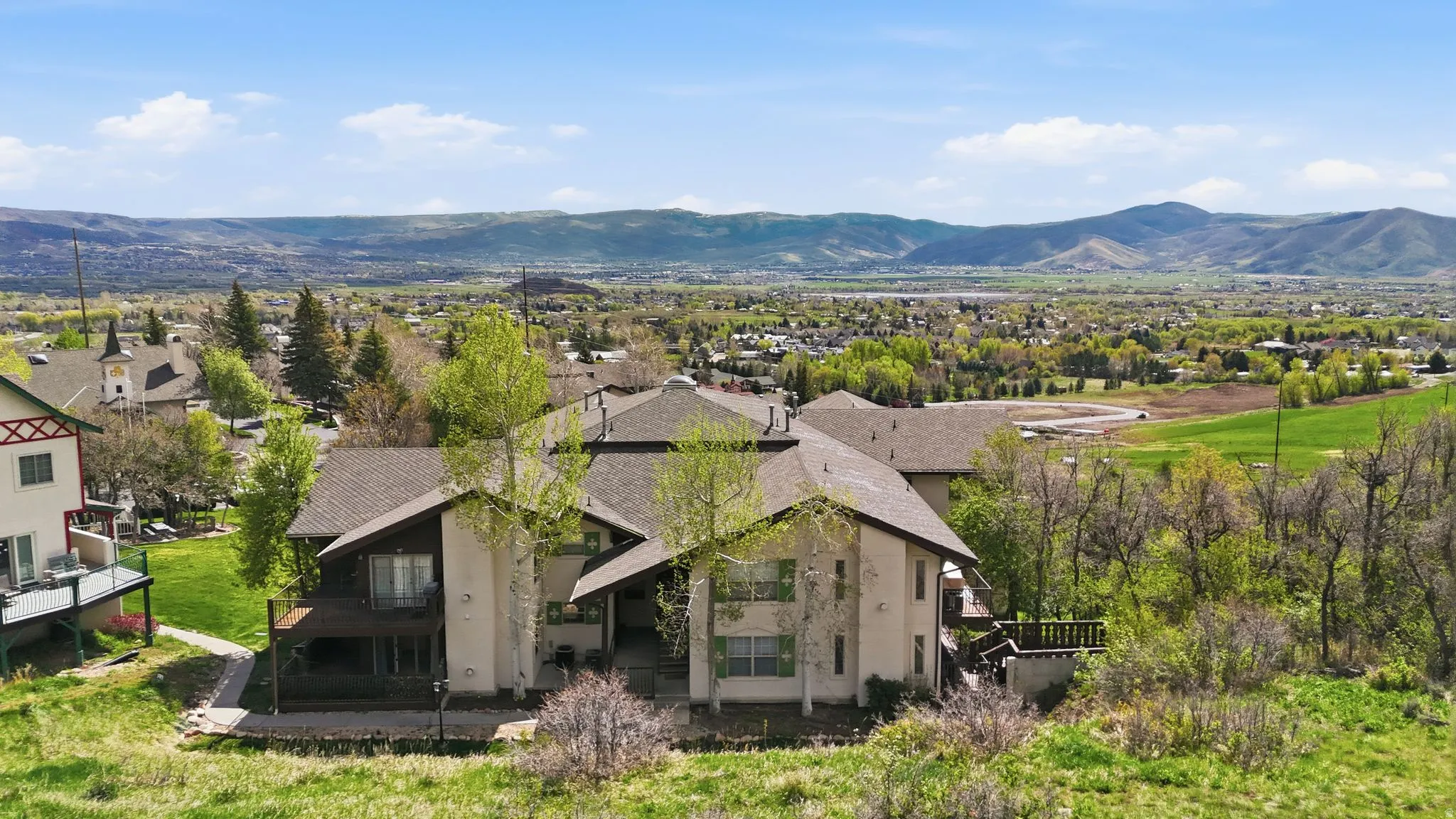 Multi-level property with exterior balconies, a private deck, and a brown shingle roof