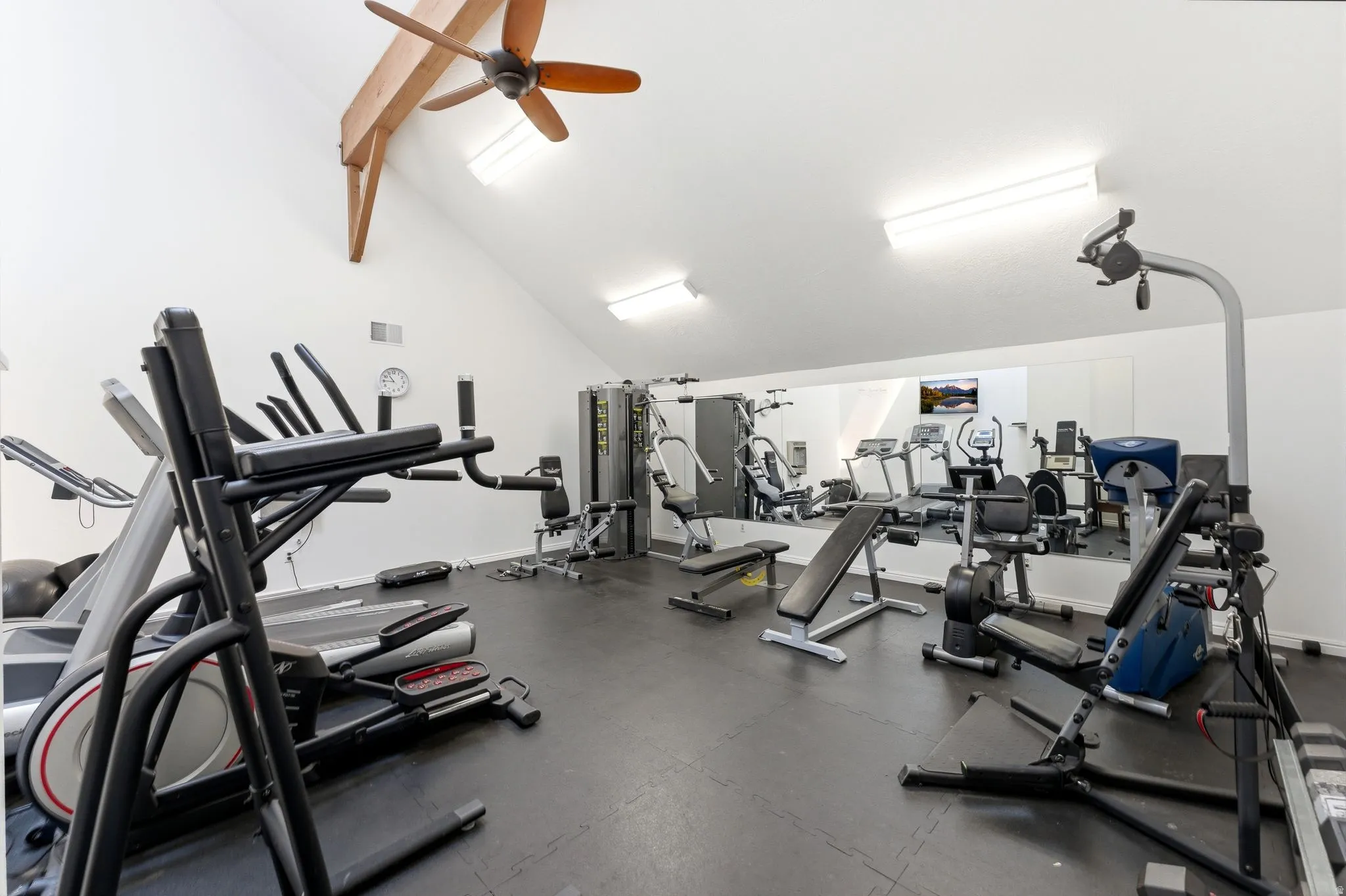 Fitness room featuring an angled ceiling with exposed wood beams, a ceiling fan, and recessed lighting