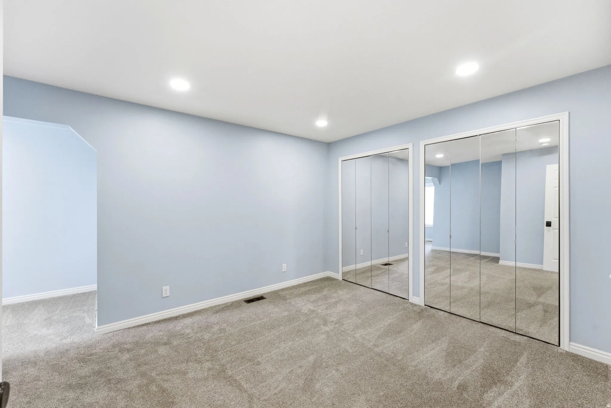 Room with light blue walls and neutral carpet flooring