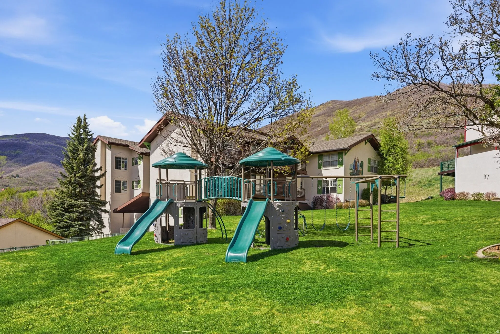 Expansive green space featuring a playground with slides, swings, and climbing elements