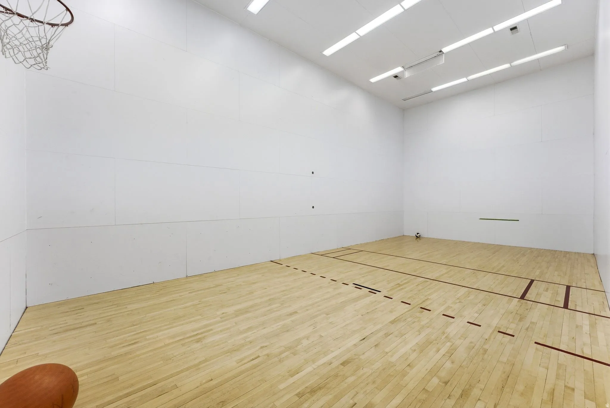 Indoor sports court featuring light wood-finish flooring with court markings