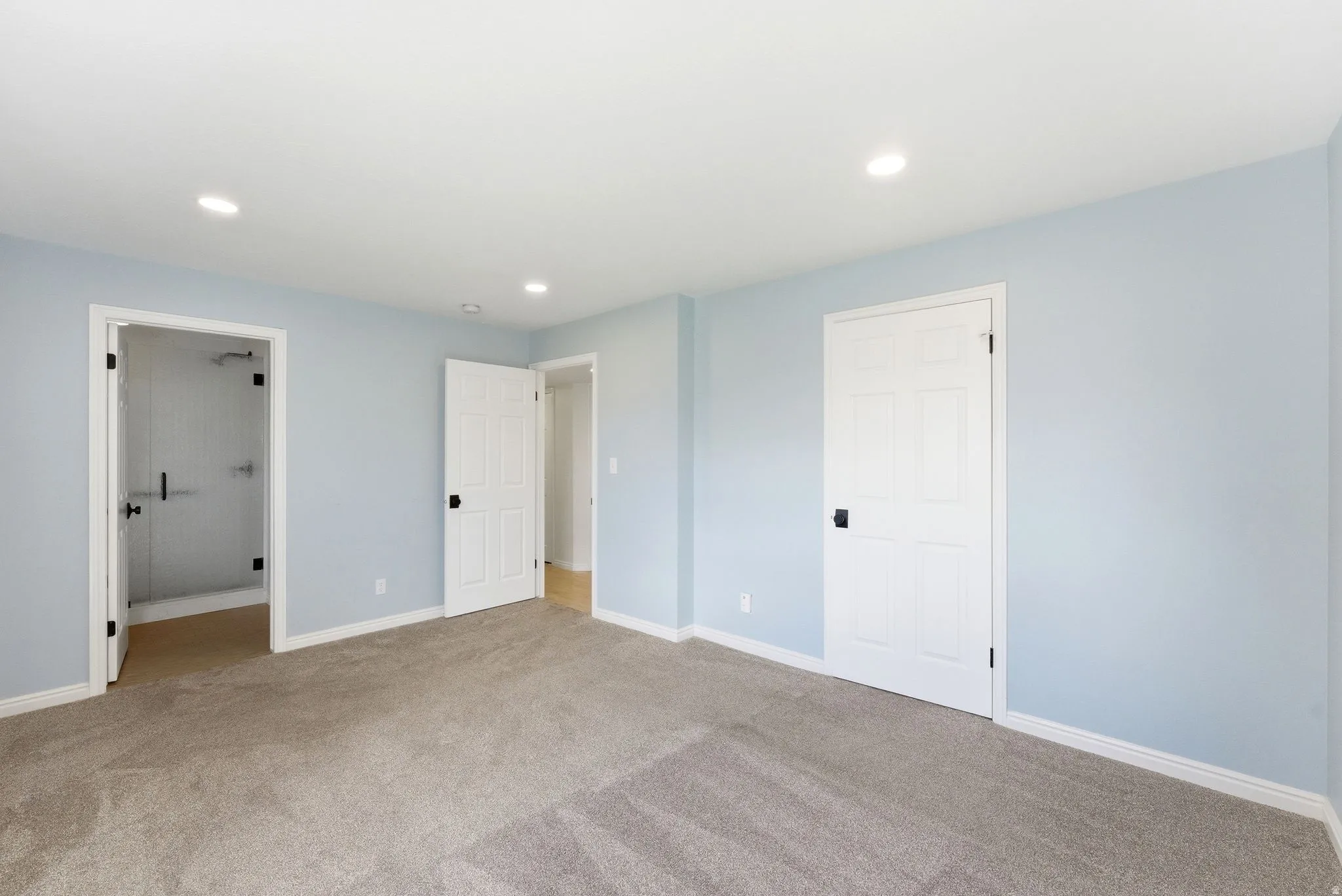 Expansive room featuring light blue walls and neutral carpet