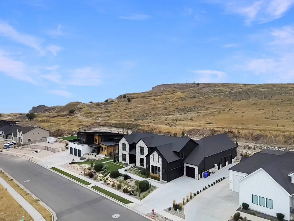 Modern architectural design with a dark facade, light stone accents, attached multiple-car garage, and a manicured front yard