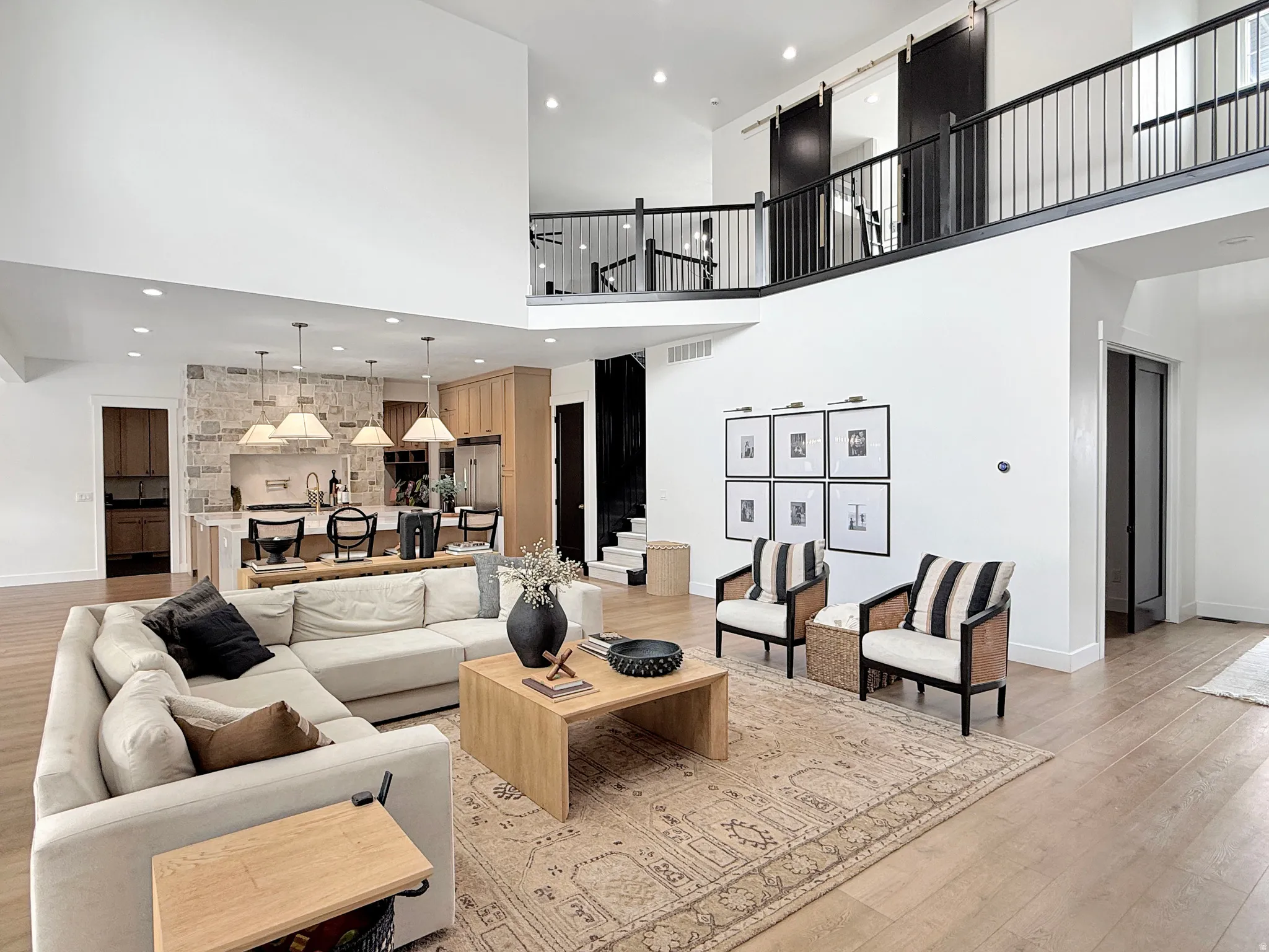 Open-concept living space featuring high ceilings, wood-finish flooring, and a second-story balcony with black railing