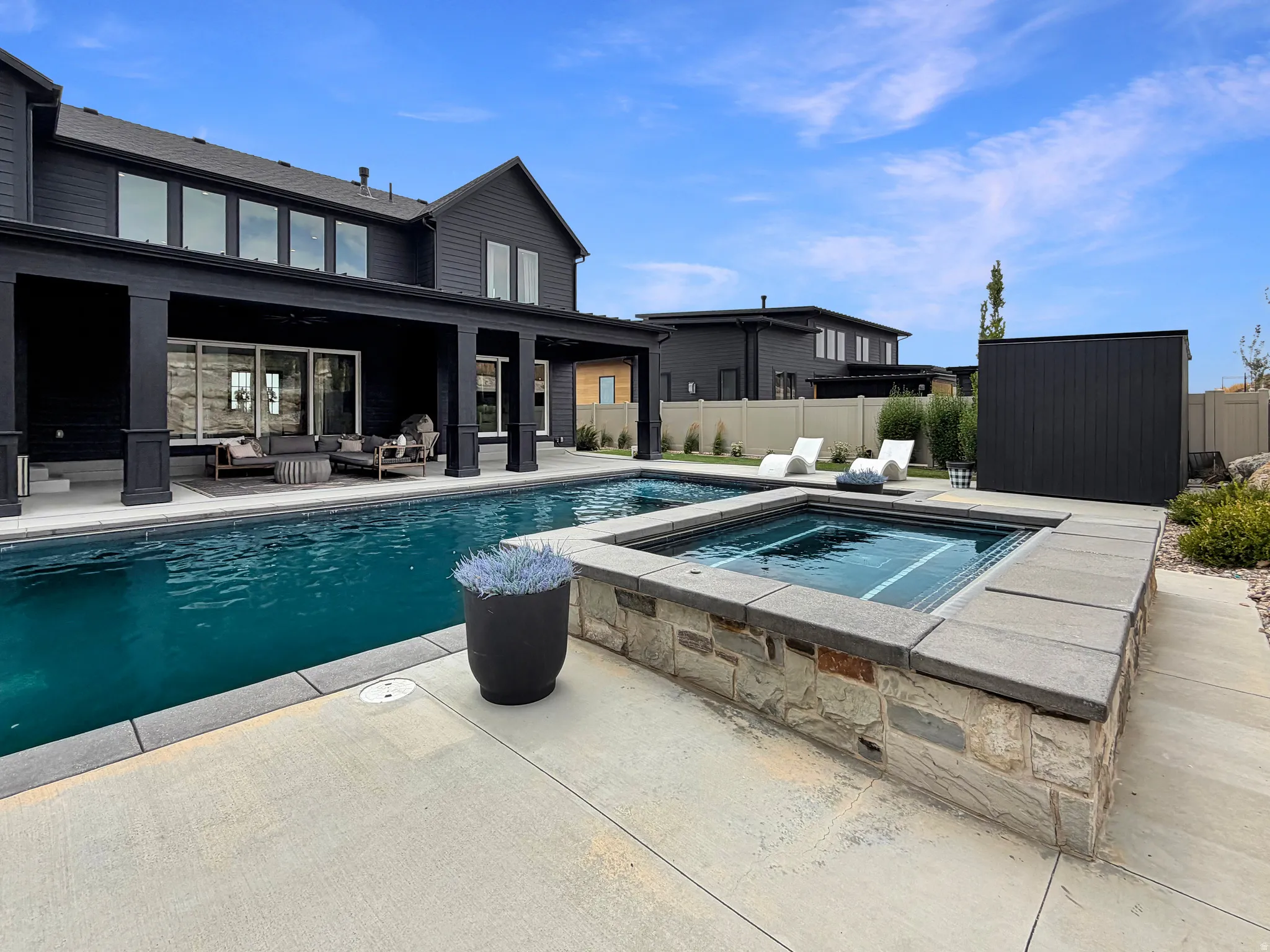 Outdoor living area featuring a swimming pool, integrated spa with stone and block surround, and a covered patio