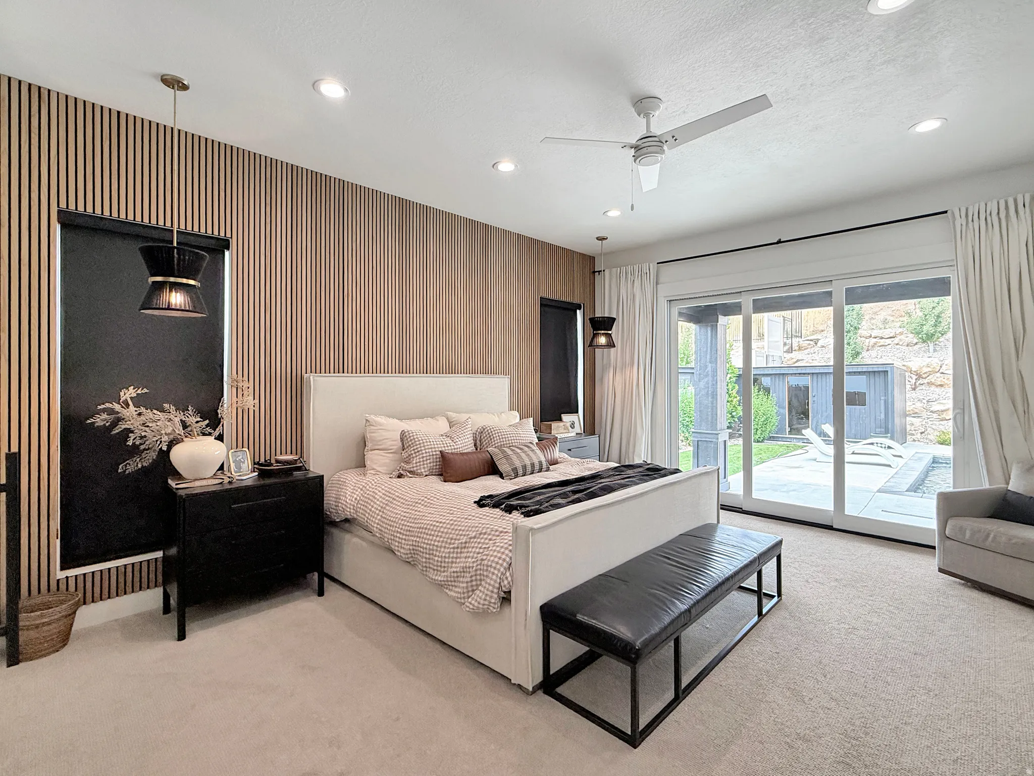 Wood panel accent wall, recessed lighting, ceiling fan, sliding glass doors, and an outdoor patio