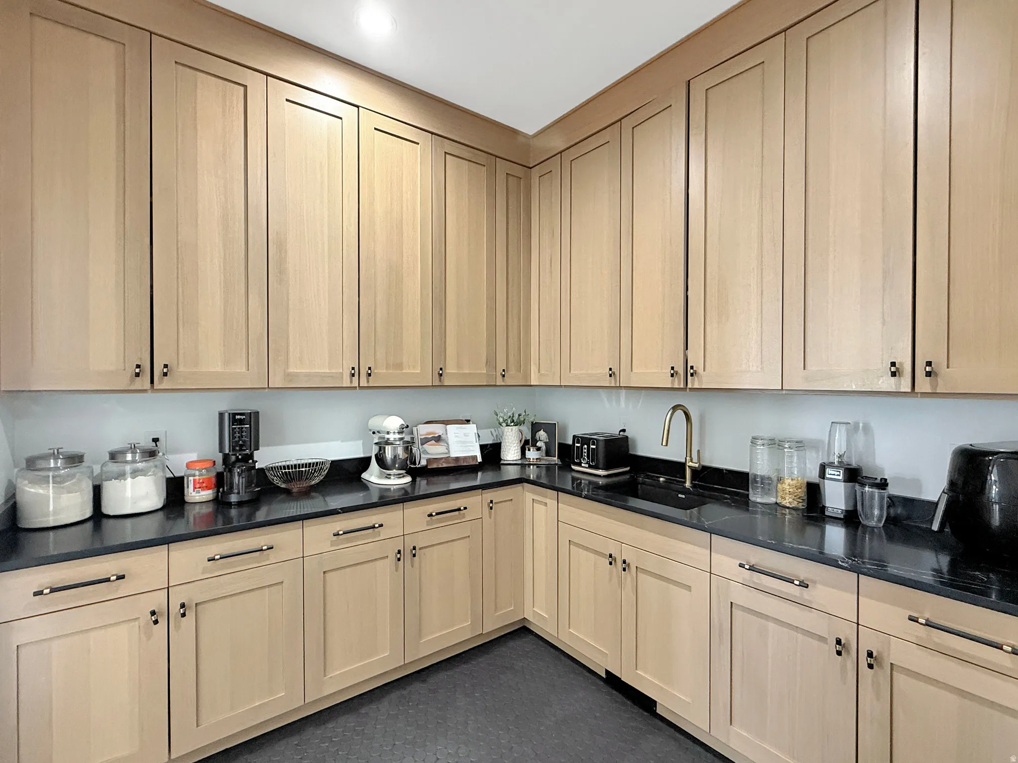 Extensive kitchen cabinetry with light wood-finish doors and dark hardware