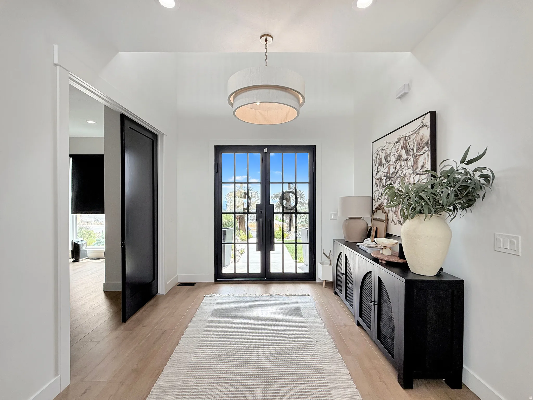 Vaulted entryway featuring wood-finish flooring, recessed lighting, and a contemporary chandelier
