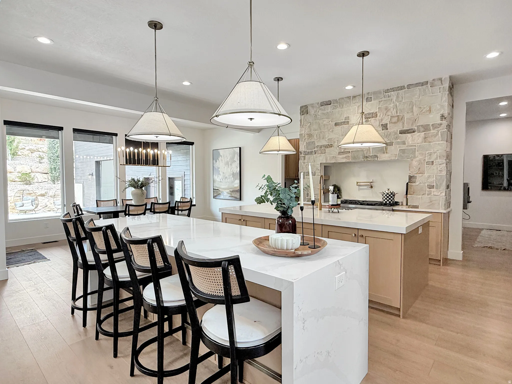 Light wood-finish flooring, stone accent wall, white countertops, built-in cabinetry, and recessed lighting