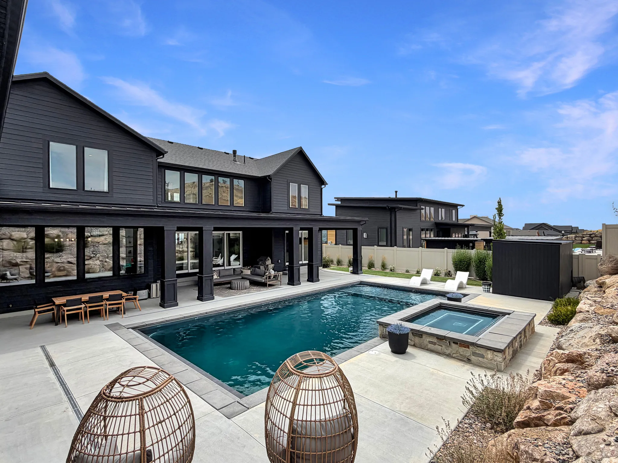 Expansive concrete patio with an in-ground swimming pool and an integrated hot tub featuring stone surround