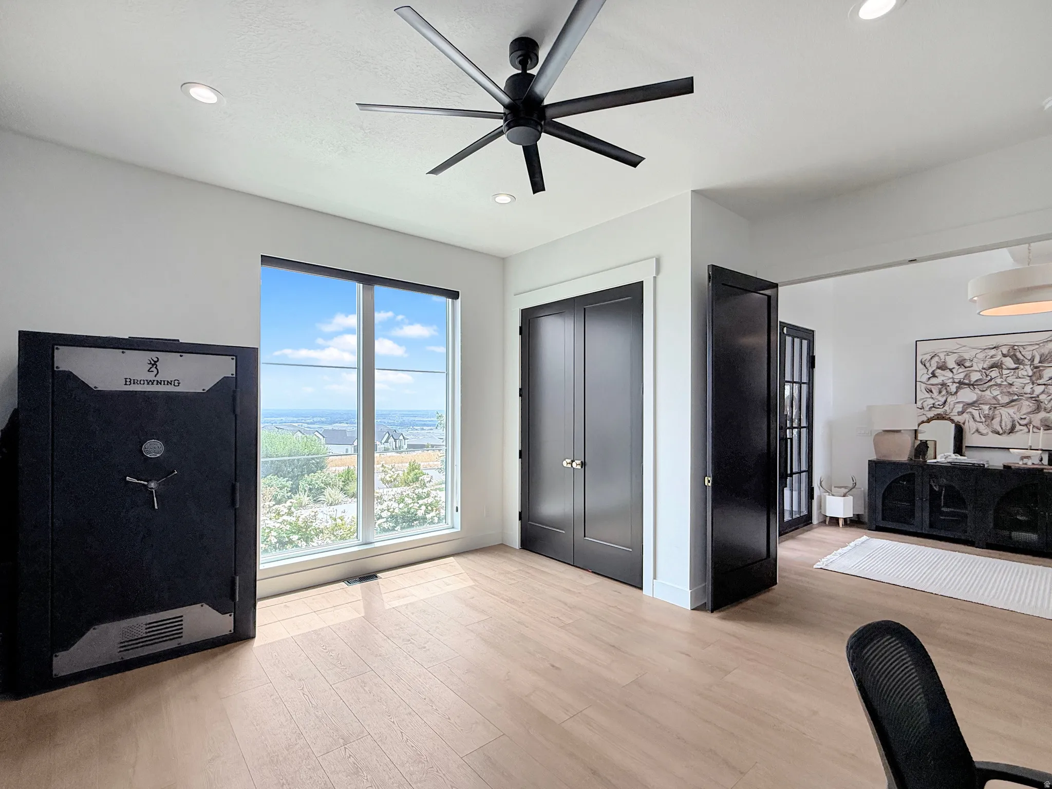 Recessed lighting, light wood-finish flooring, a contemporary ceiling fan, and large windows